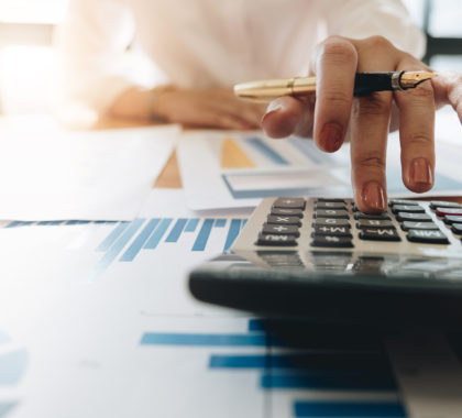 Close up Business woman using calculator and laptop for do math finance on wooden desk in office and business working background, tax, accounting, statistics and analytic research concept